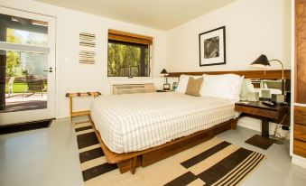 a large bed with white sheets and a wooden headboard is in a room with black and white striped rug at Little Beaver Inn