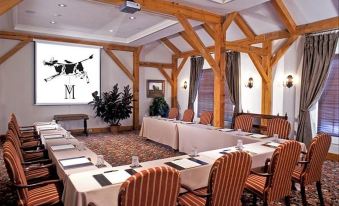 a conference room with a large table surrounded by chairs and a projection screen on the wall at The Inn at Montchanin Village