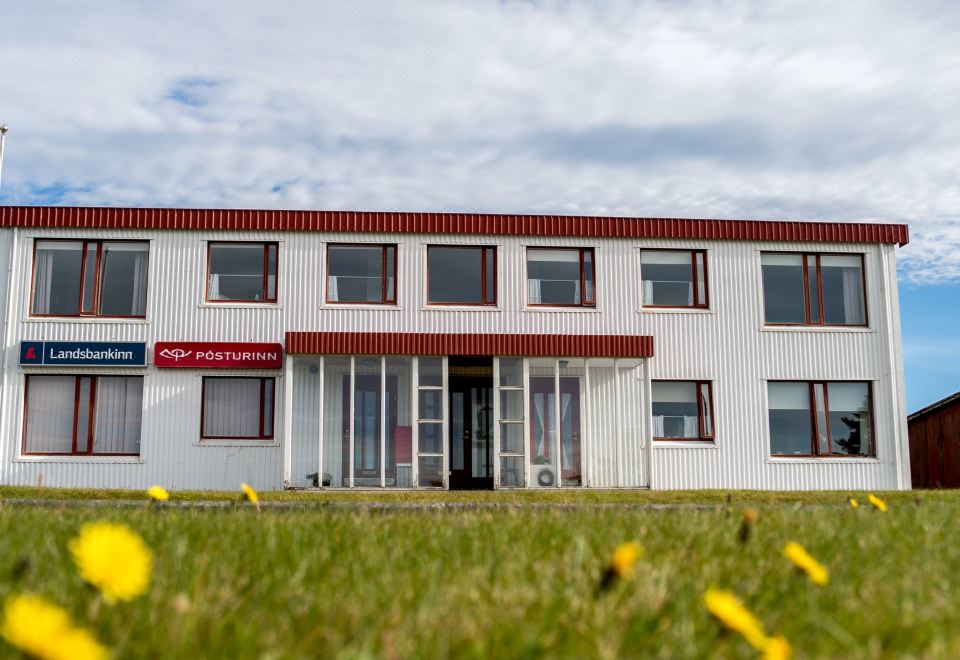 a white building with red trim , surrounded by green grass and a cloudy sky , under a cloudy sky at The View Apartments