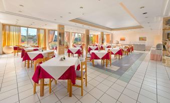 a large dining room with multiple tables and chairs arranged for a group of people at Bayside Hotel Katsaras