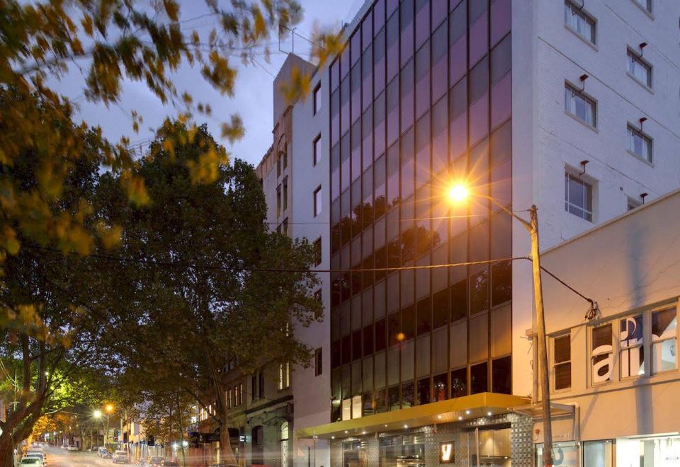 a city street with a tall building on the left side and a car driving down the road at 57Hotel