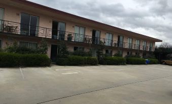 a large , pink building with a balcony and balconies is situated in front of a parking lot at Crest Motor Inn