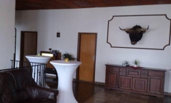 a living room with a white round table and brown leather chair , a cow skull mounted on the wall , and a brown cabinet at Weißes Haus