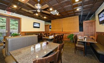 a restaurant with wooden ceiling , white walls , and various seating arrangements including tables , chairs , and a television at Best Western the Inn at Ramsey