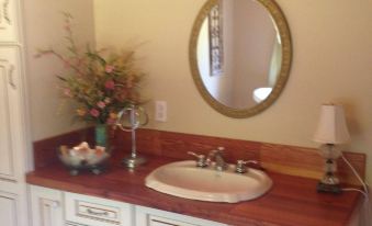 a bathroom sink with a red countertop and white cabinets , featuring a vase of flowers and a mirror at Concord Inn