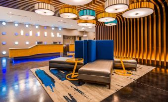 a modern and stylish hotel lobby with blue and gold booths , yellow pendant lights , and wooden flooring at GLo Best Western DeSoto Dallas