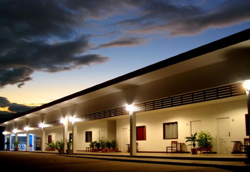 a building with a white exterior and large windows , lit up at night with a path leading to the entrance at Tonnam Resort