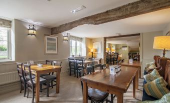 a restaurant with wooden tables and chairs , a large window , and hanging lights on the ceiling at Wild Thyme & Honey