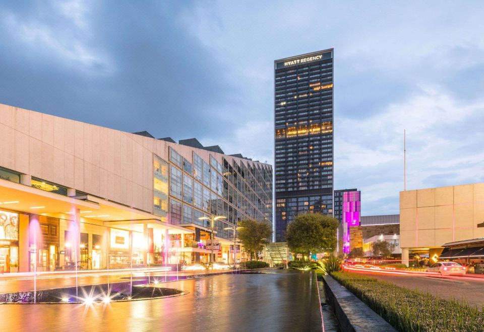 a city street with a tall building in the background , and a fountain in the foreground at Hyatt Regency Andares Guadalajara