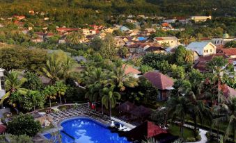 aerial view of a resort with a pool surrounded by palm trees and a mountain in the background at Sahid Bela Ternate