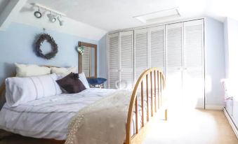 a bedroom with a wooden bed , white curtains , and a wreath hanging on the wall at Garden View