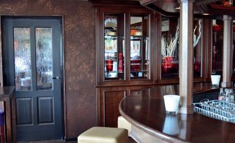 a bar with a curved wooden counter and stools , surrounded by glass cabinets and a fire extinguisher on the wall at Fletcher Hotel - Restaurant Heiloo