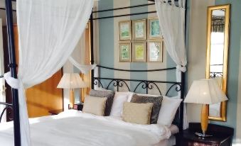 a large bed with a white canopy and black metal frame is shown in a bedroom at Manor Hotel