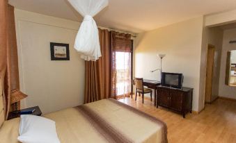 a hotel room with a bed , television , and sliding glass door leading to a balcony at Belvedere Hotel