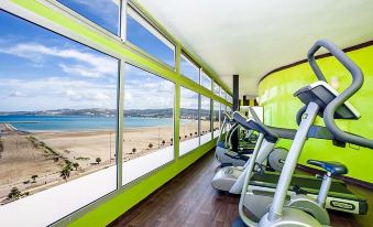 a gym with green walls and a large window , offering a view of the beach and mountains at Marina Bay City Center