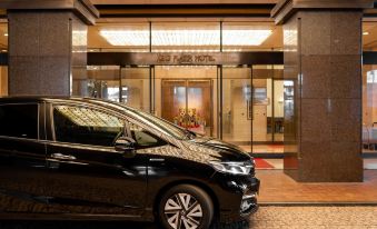 "a black car parked in front of a hotel entrance with a sign that says "" the hotel ""." at Keio Plaza Hotel Hachioji