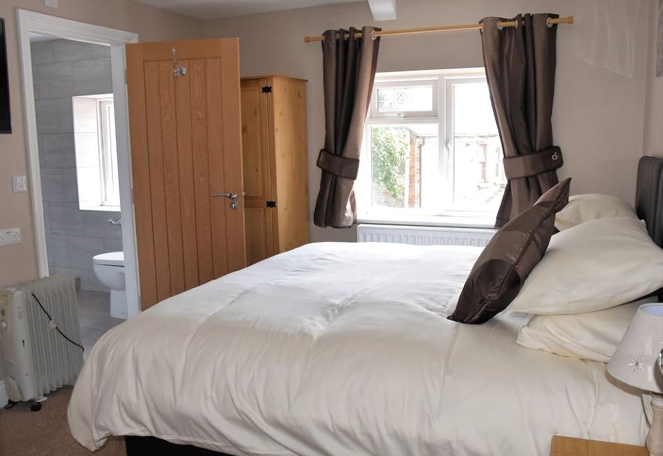 a clean and well - organized bedroom with a large bed , a bathroom visible through a window , and a closet at The Red Lion