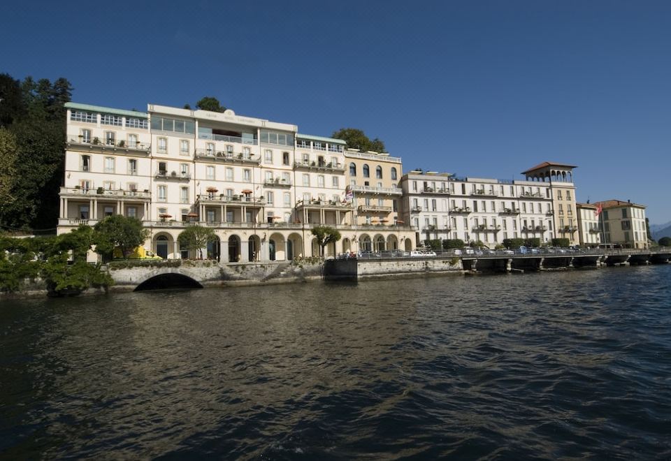 a city with buildings along the water 's edge , some of which are older and ornate at Grand Hotel Cadenabbia