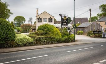 a quaint english country inn with a stone building , surrounded by trees and bushes , situated on a country road at The Sawley Arms