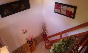 a staircase with wooden steps and a red flower arrangement on the floor , leading to a room with a painting on the wall at La Cure