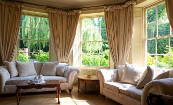 a cozy living room with two white couches and a large window , allowing natural light to fill the space at Risley Hall Hotel