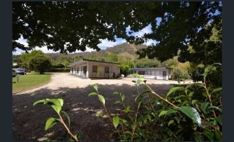 a large house surrounded by trees and bushes , with a driveway leading up to it at Mount Beauty Motor Inn