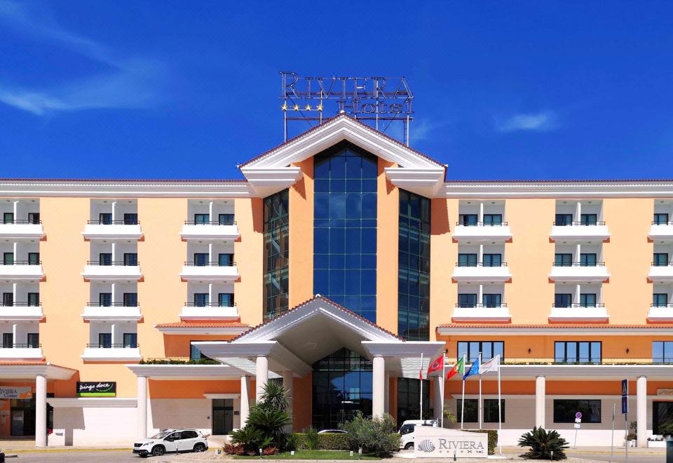 a large hotel building with a blue and yellow facade , located in a city setting at Riviera Hotel