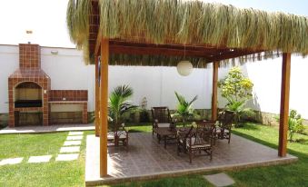 a backyard with a wooden gazebo , surrounded by lush greenery and potted plants , providing a relaxing outdoor space at Costa Esmeralda