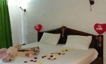 a bed with a white comforter and pillows , decorated with heart - shaped balloons and hearts on the floor at Hotel la Perla