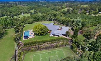 aerial view of a large house with a tennis court and pool , surrounded by lush greenery at Ferncrest