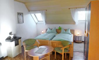 a cozy bedroom with two beds , a table and chairs , and a window with a view of the city at Zerna