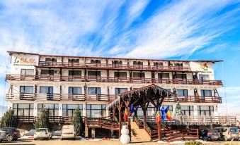 a large hotel building with multiple floors , balconies , and a wooden deck , situated in front of a blue sky with clouds at Hotel La Dolce Vita