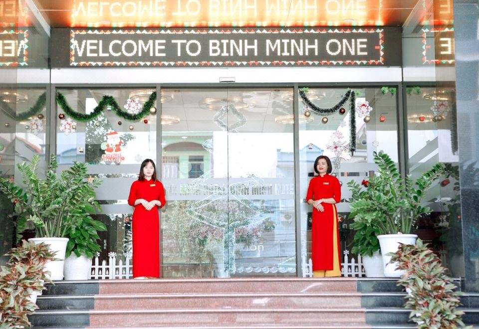 "two women in red dresses standing on a staircase in front of a building with the sign "" welcome to binh minh one .""." at Binh Minh Hotel