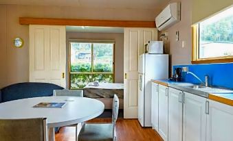 a modern kitchen with white cabinets , a dining table , and a window overlooking the outdoors at Discovery Parks - Hobart