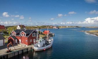 a picturesque coastal town with red and white buildings , boats docked in the water , and a clear blue sky at Helgeland