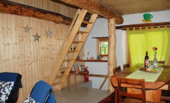 a wooden house with a ladder leading to a loft area , where a dining table and chairs at Camblee