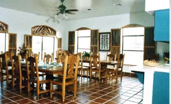 a large dining room with wooden tables and chairs , a ceiling fan , and tile flooring at Casa de San Pedro Bed & Breakfast