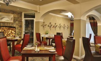 a dining room with red chairs and tables , along with decorative plates on the table at Best Western Heronston Hotel  Spa