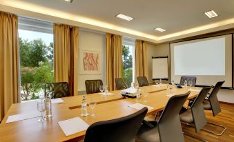 a conference room with a long wooden table , several chairs , and a screen on the wall at La Luna Hotel - All Inclusive