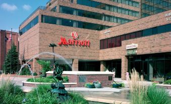 a large brick building with a red sign and a fountain in front of it at Marriott East Lansing at University Place