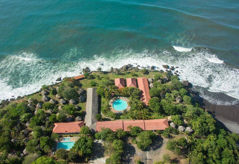 aerial view of a resort on an island surrounded by the ocean , with a pool and grassy area in the background at Atami Escape Resort