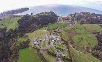 an aerial view of a rural area with a large body of water in the background at Hot Water Beach Top 10 Holiday Park