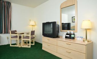 a living room with a green carpet , wooden furniture , and a tv on a dresser at Americas Best Value Inn Eloy/Casa Grande