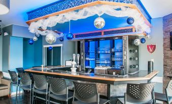 a bar with blue walls , white ceiling , and silver disco balls hanging from the ceiling at Hotel le Versailles