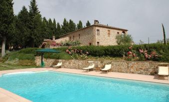a large pool is surrounded by a stone wall and lounge chairs , with a house in the background at Abbadia Sicille Relais
