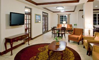 a spacious living room with wooden furniture , including a couch , chairs , and a dining table at Holiday Inn Express & Suites Jackson