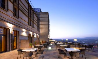 a rooftop patio with tables and chairs , as well as a view of the city skyline at Parador de Lorca