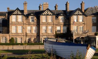 a large , historic building with multiple chimneys and a blue boat on the ground , under a clear sky at Wentworth Hotel