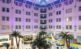 a large hotel lobby with a high ceiling , palm trees , and a pool area , under a purple starry ceiling at Thon Hotel Oslofjord