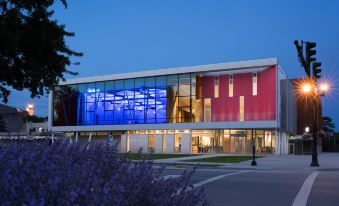 a modern building with a red and blue facade is lit up at night , surrounded by greenery at The Hotel at Oberlin